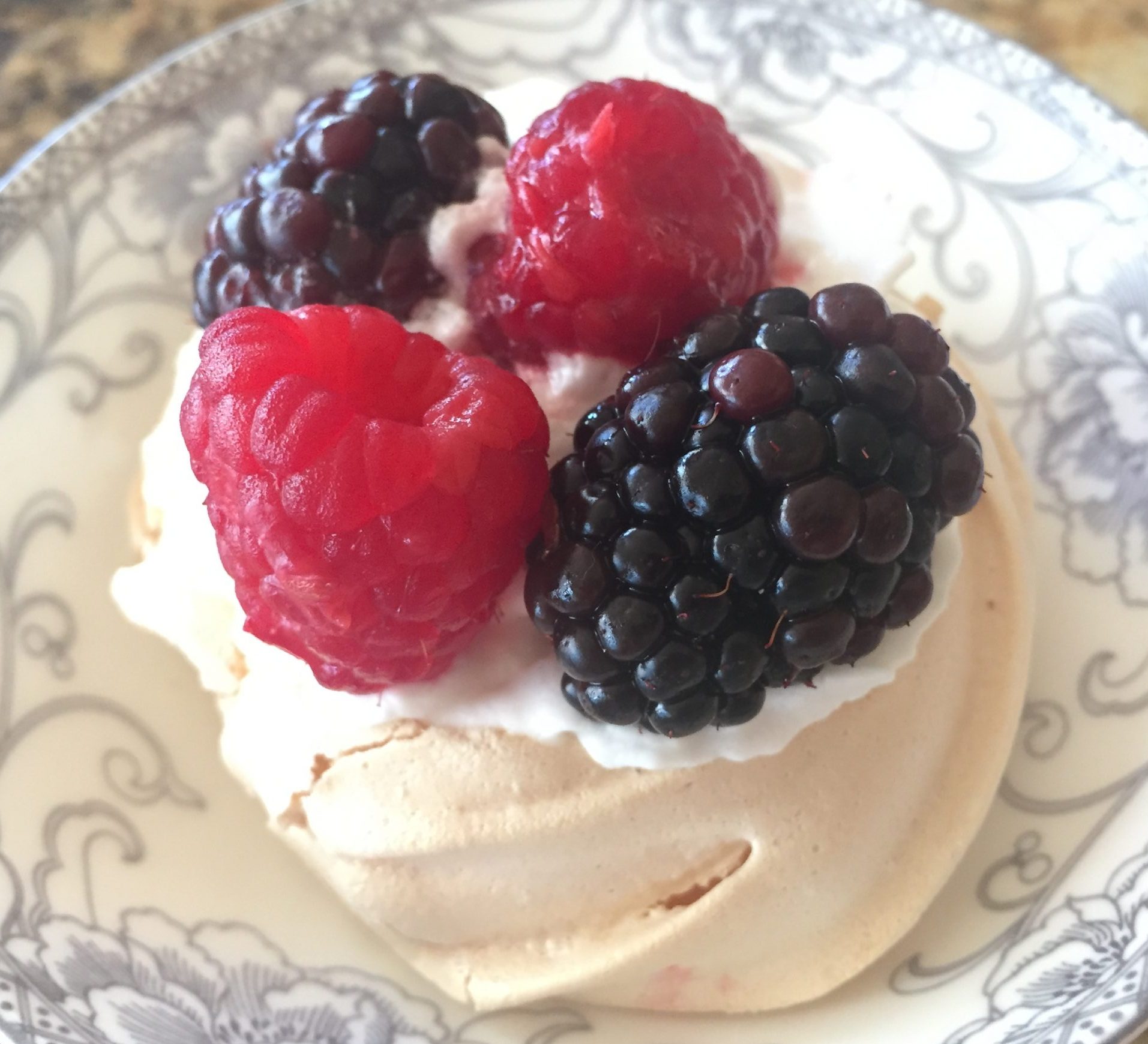 pavlova nest topped with whipped cream and fresh berries