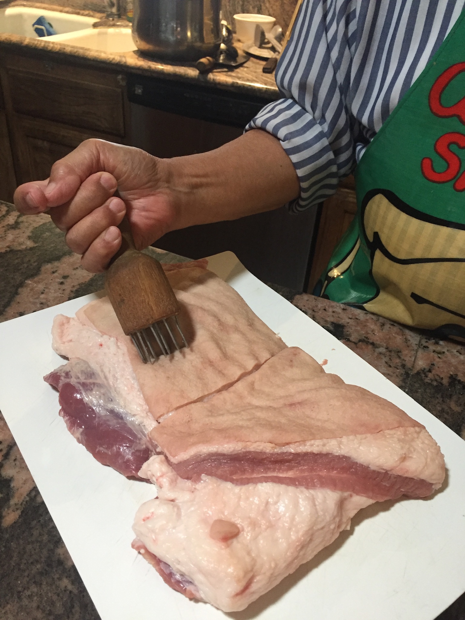 Using the meat tenderizer to puncture the pork skin.