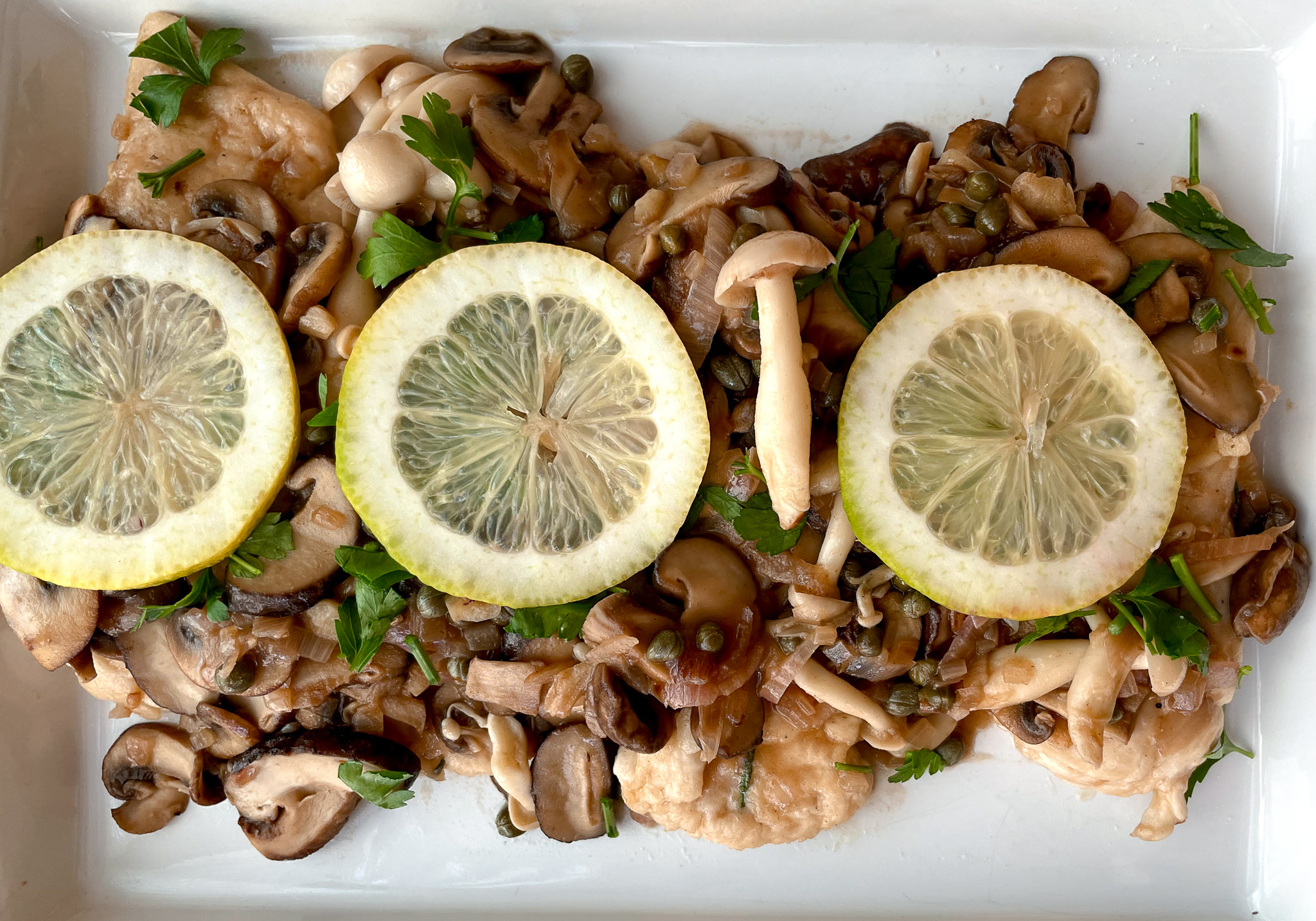 Chicken piccata with assorted mushrooms.